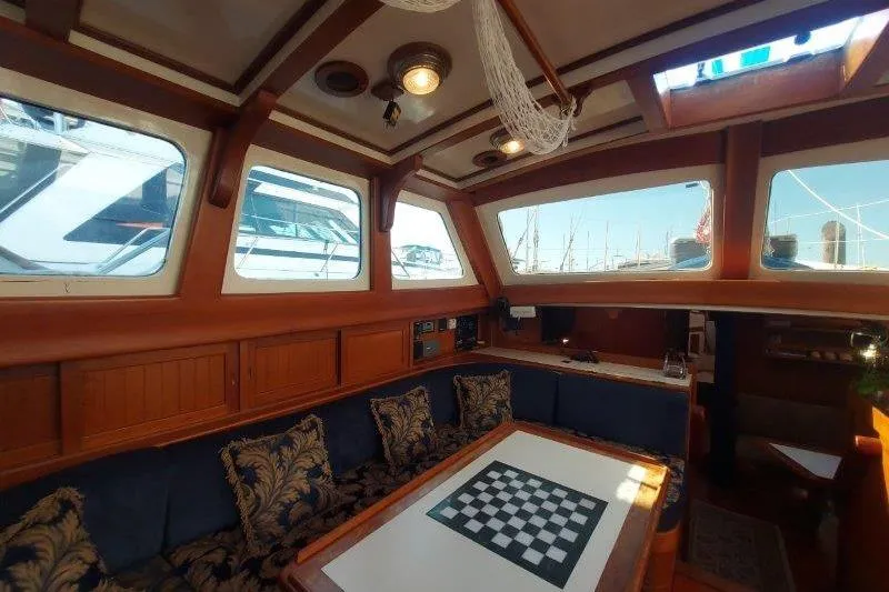 Tenacious Yacht Photos Pics Interior of a 1987 Mikelson 50 yacht with a cozy seating area and chessboard table.