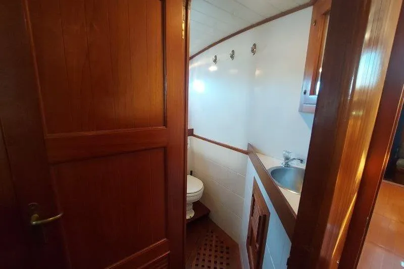 Tenacious Yacht Photos Pics 1987 Mikelson 50 yacht bathroom with wooden door, sink, and toilet.