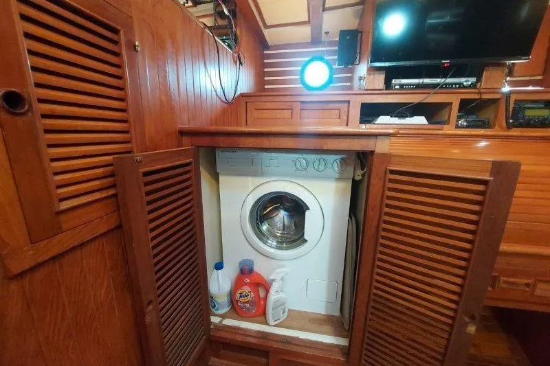 Tenacious Yacht Photos Pics Laundry area inside a 1987 Mikelson 50 yacht with wooden cabinetry.