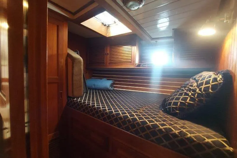Tenacious Yacht Photos Pics Cozy cabin interior of 1987 Mikelson 50 yacht with wooden finishes and patterned bedding.