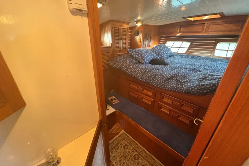 Tenacious Yacht Photos Pics Cozy bedroom interior of 1987 Mikelson 50 yacht with wooden furnishings and blue bedding.