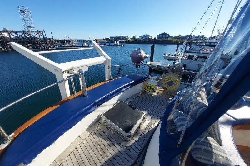 Tenacious Yacht Photos Pics 1987 Mikelson 50 yacht deck with blue seating, docked in a marina under clear skies.
