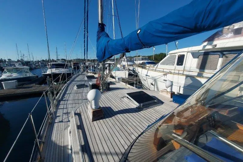 Tenacious Yacht Photos Pics 1987 Mikelson 50 yacht docked at marina, featuring spacious deck and blue sail cover.