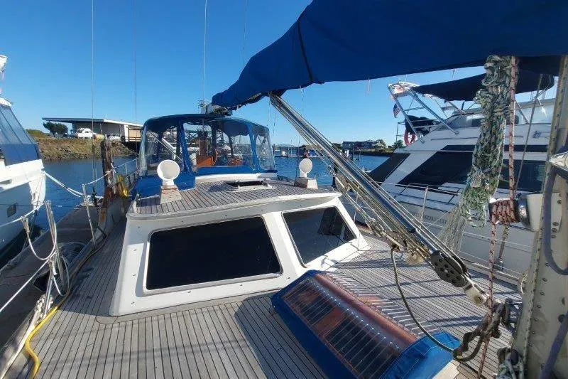 Tenacious Yacht Photos Pics 1987 Mikelson 50 yacht docked, featuring a spacious deck and blue canopy.