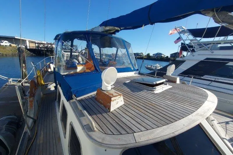Tenacious Yacht Photos Pics 1987 Mikelson 50 yacht docked, featuring a blue canopy and wooden deck.