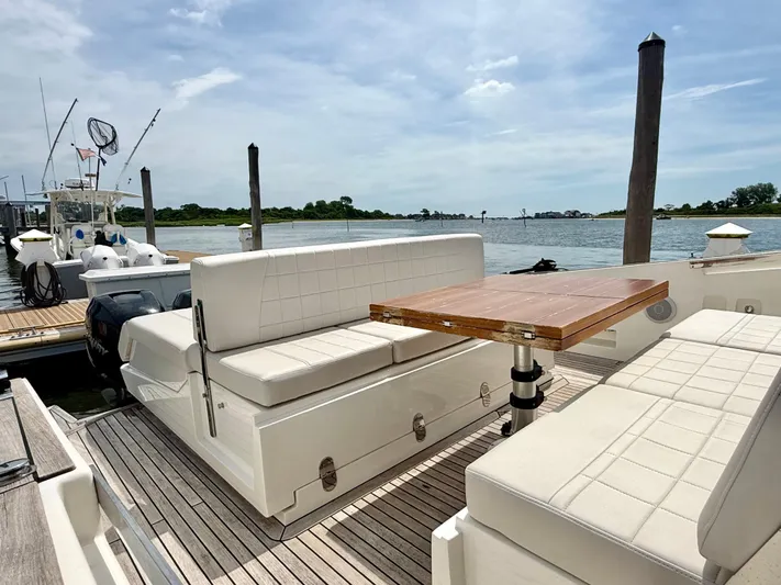  Yacht Photos Pics 2023 Astondoa 377 Coupe Outboard, elegant seating area with wooden table, docked by the water.