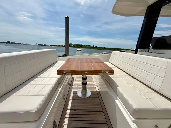  Yacht Photos Pics 2023 Astondoa 377 Coupe Outboard, luxurious deck seating with wooden table, scenic water view.