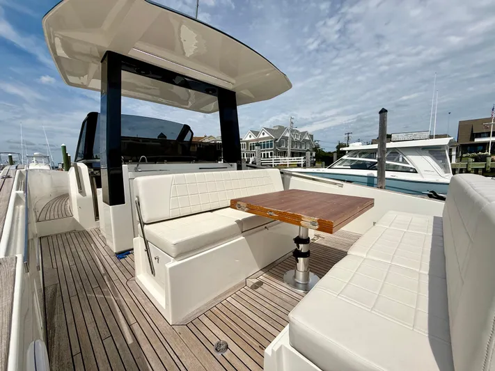  Yacht Photos Pics 2023 Astondoa 377 Coupe Outboard yacht with elegant seating and wooden table on deck.