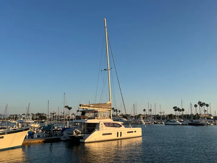  Yacht Photos Pics 2019 Leopard 58 yacht docked in a marina at sunset, surrounded by sailboats.