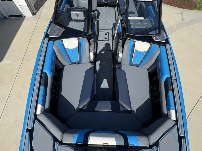  Yacht Photos Pics 2024 Malibu M242 boat interior with blue and gray seating, viewed from above.