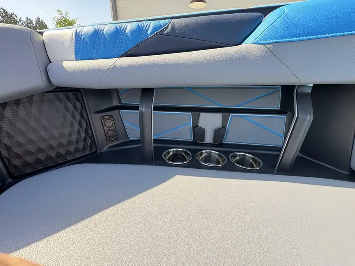  Yacht Photos Pics 2024 Malibu M242 boat interior with blue and gray seating, cup holders, and speaker.