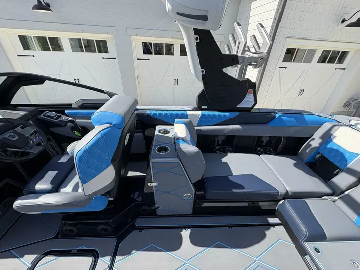  Yacht Photos Pics 2024 Malibu M242 boat interior with blue and gray seating, cup holders, and modern design.