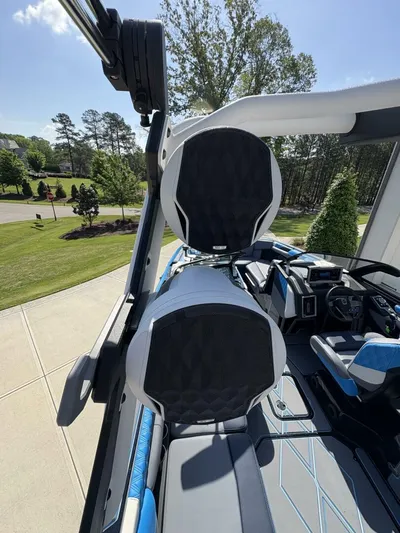  Yacht Photos Pics 2024 Malibu M242 boat interior with speakers and seating, parked outdoors on a sunny day.