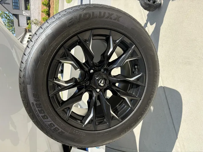  Yacht Photos Pics 2024 Malibu M242 black alloy wheel with Evolux tire on concrete driveway.