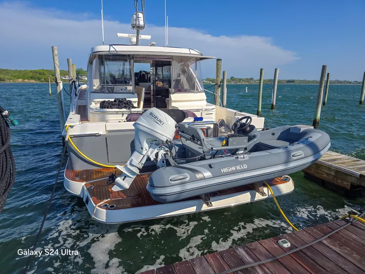 Scorpius Yacht Photos Pics 2022 Riviera 505 SUV yacht docked with inflatable boat on lift.