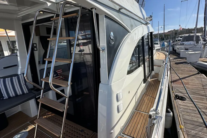 Vitamin Sea Yacht Photos Pics 2023 Beneteau Antares 11 Fly yacht with sleek design and wooden deck at marina.