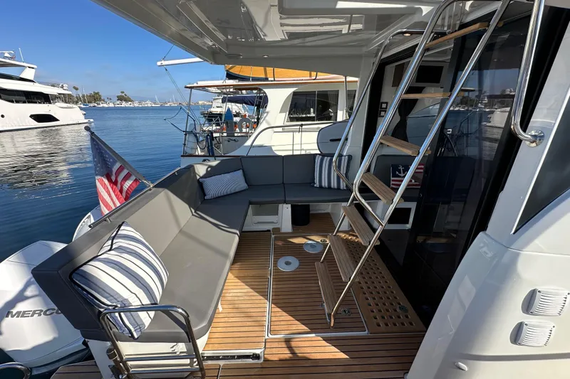 Vitamin Sea Yacht Photos Pics 2023 Beneteau Antares 11 Fly yacht with outdoor seating and ladder, docked at marina.
