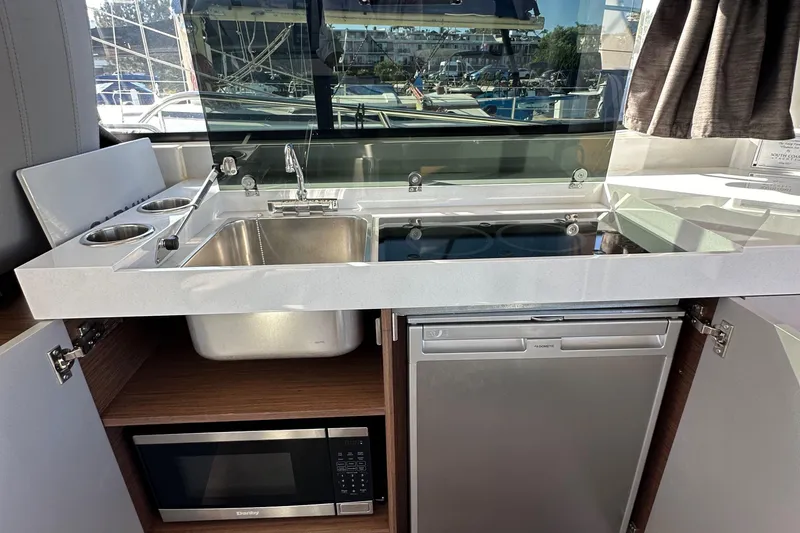 Vitamin Sea Yacht Photos Pics Modern kitchen area in 2023 Beneteau Antares 11 Fly yacht with sink, stove, and microwave.