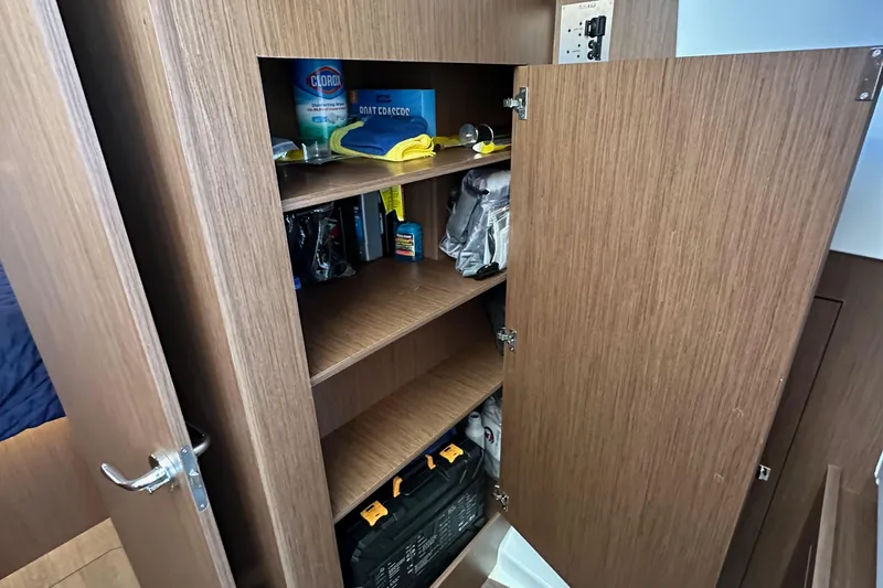Vitamin Sea Yacht Photos Pics Wooden storage cabinet on Beneteau Antares 11 Fly 2023, stocked with cleaning supplies.