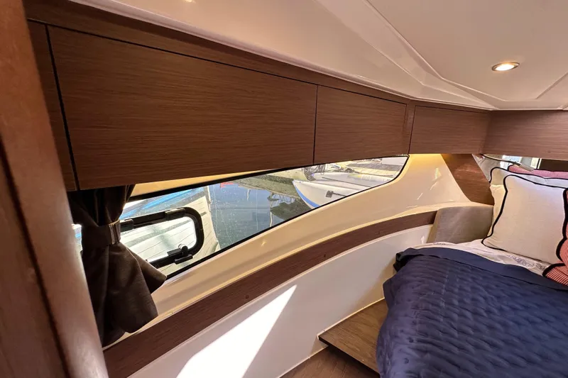 Vitamin Sea Yacht Photos Pics Interior cabin of 2023 Beneteau Antares 11 Fly, featuring wood cabinetry and cozy bedding.