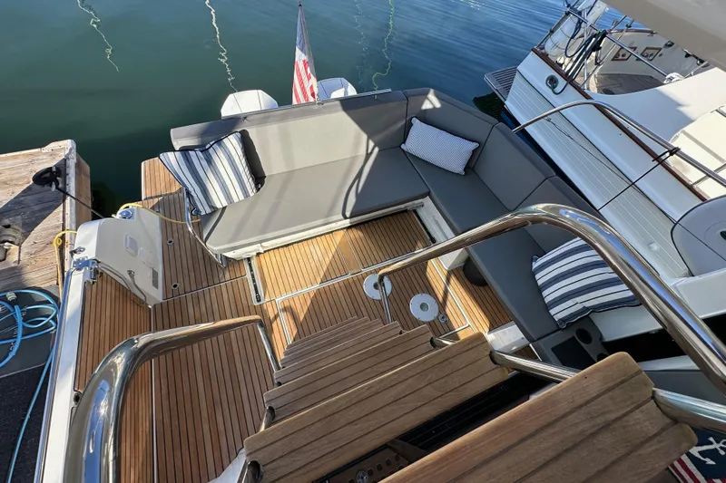 Vitamin Sea Yacht Photos Pics 2023 Beneteau Antares 11 Fly yacht deck with cushioned seating and wooden flooring.