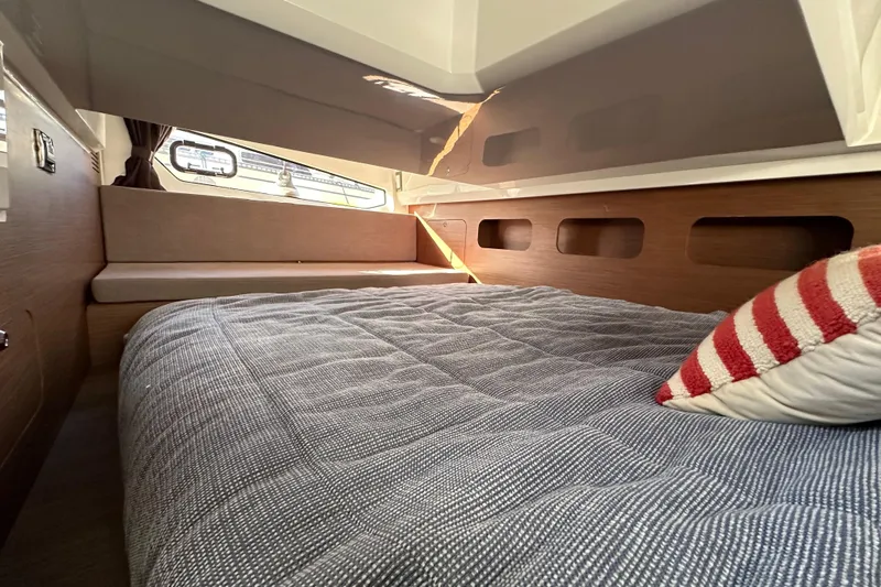 Vitamin Sea Yacht Photos Pics 2023 Beneteau Antares 11 Fly cabin interior with cozy bed and striped pillow.
