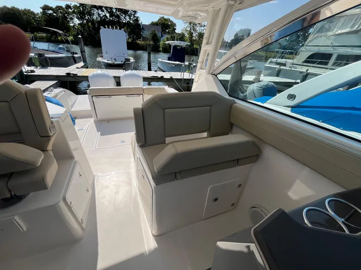  Yacht Photos Pics 2018 Pursuit DC 295 Dual Console boat interior with seating and docked boats in background.