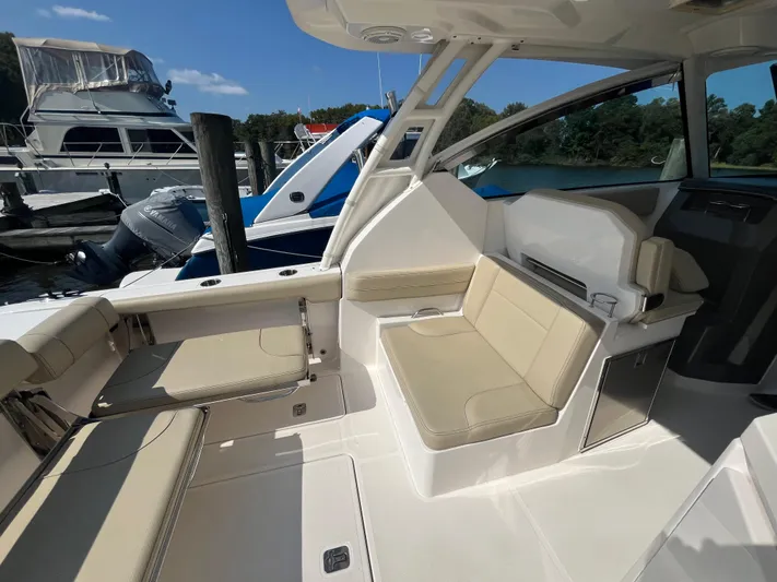  Yacht Photos Pics 2018 Pursuit DC 295 Dual Console boat interior with beige seating at a marina.