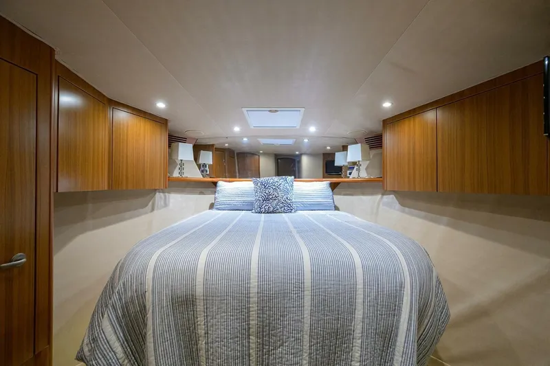 Pryorities Yacht Photos Pics Luxurious bedroom interior of 2008 Viking 60 Convertible yacht with striped bedding and wooden cabinets.