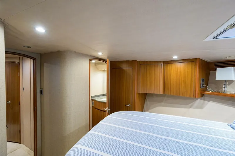 Pryorities Yacht Photos Pics Interior of 2008 Viking 60 Convertible yacht bedroom with wooden cabinets and striped bedding.