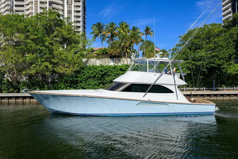 Pryorities Yacht Photos Pics 2008 Viking 60 Convertible yacht cruising near lush greenery and tall buildings.