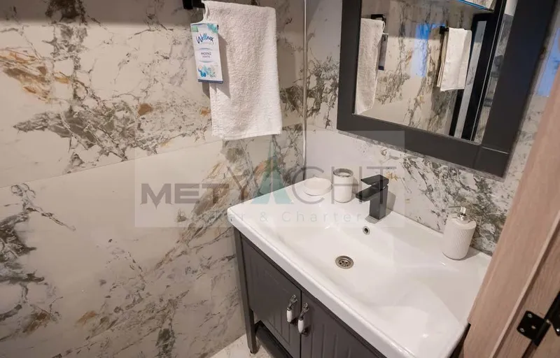  Yacht Photos Pics Modern bathroom with marble walls, sleek sink, and mirror on a 2024 Custom Trawler.