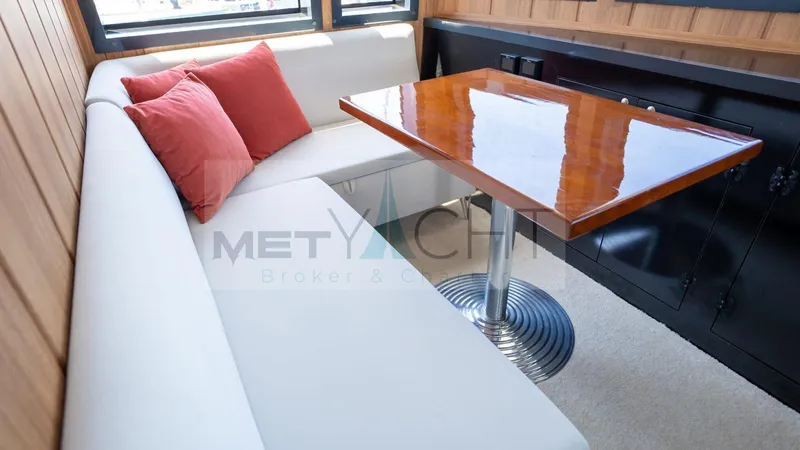  Yacht Photos Pics Luxurious 2024 Custom Trawler interior with white seating, wooden table, and red cushions.