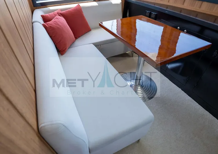  Yacht Photos Pics 2024 Custom Trawler interior with white seating, red cushions, and polished wooden table.