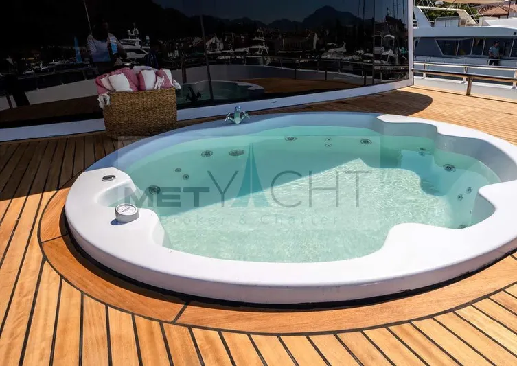  Yacht Photos Pics Luxury yacht deck with jacuzzi, 2024 Custom Trawler, featuring teak flooring and scenic marina view.