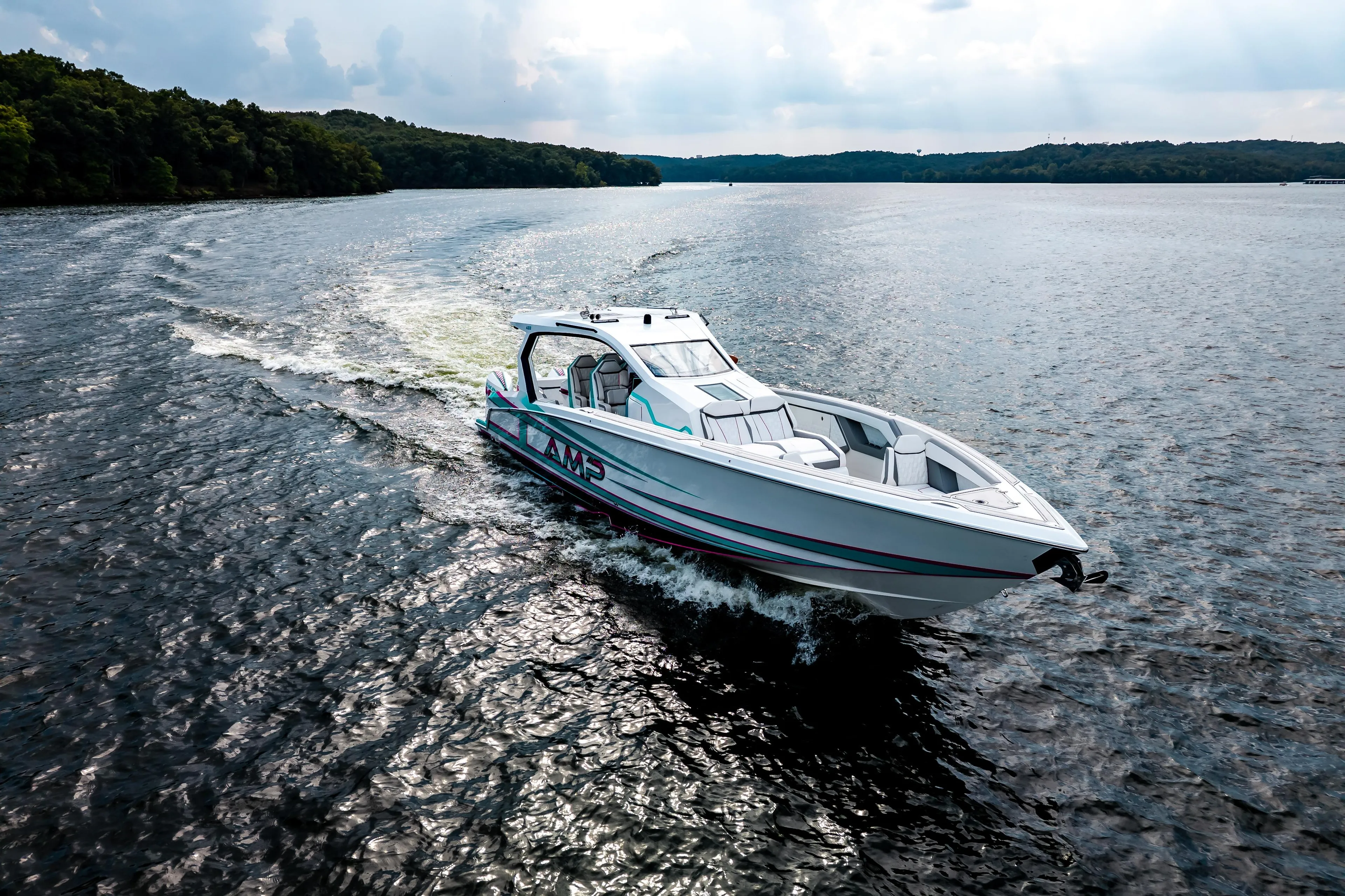 A sleek AMP 443 boat cruising on a scenic lake, 2025 model.