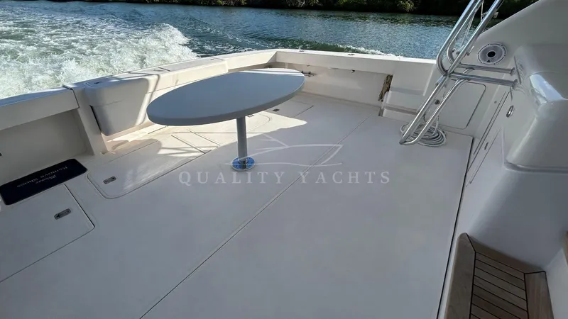 Sin Plan Yacht Photos Pics Bertram 630E 2005 yacht deck with table, cruising on water.