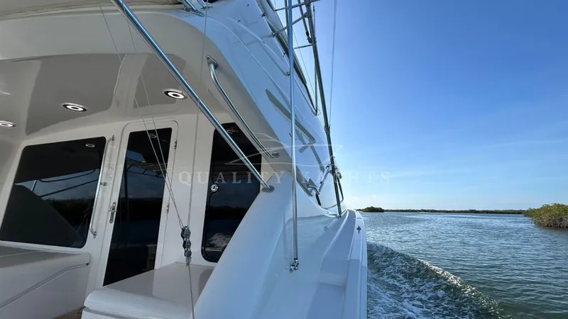 Sin Plan Yacht Photos Pics 2005 Bertram 630E yacht cruising on calm waters under a clear blue sky.