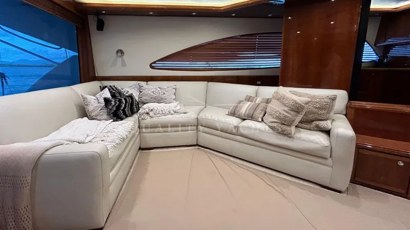 Sin Plan Yacht Photos Pics Luxurious interior of a 2005 Bertram 630E yacht with plush white seating and decorative pillows.