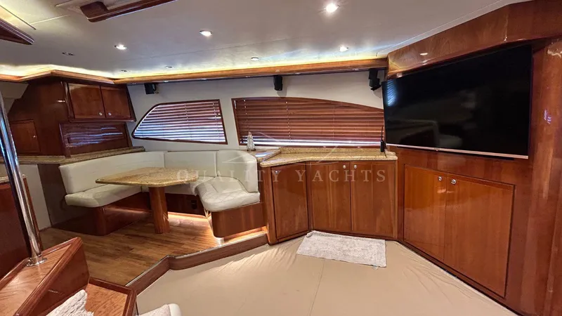 Sin Plan Yacht Photos Pics Luxurious interior of a 2005 Bertram 630E yacht with wood finishes and a dining area.