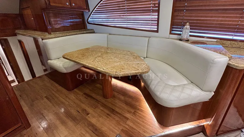 Sin Plan Yacht Photos Pics Luxurious dining area in a 2005 Bertram 630E yacht with wooden flooring and leather seating.