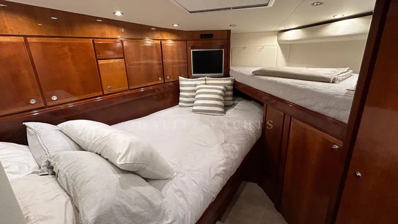 Sin Plan Yacht Photos Pics Luxurious cabin interior of a 2005 Bertram 630E yacht with wooden finishes and cozy bedding.