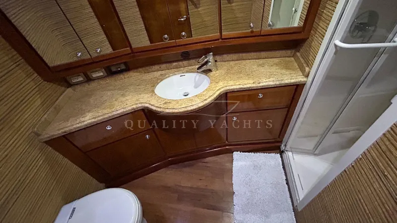 Sin Plan Yacht Photos Pics Luxurious bathroom in a 2005 Bertram 630E yacht with granite countertop and wooden cabinetry.