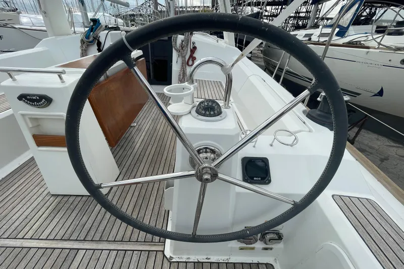 Moonshadow Yacht Photos Pics Steering wheel of a 2016 Beneteau Oceanis 38 sailboat, docked in a marina.