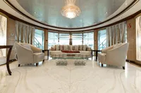 Luxurious yacht interior with elegant seating, glass table, and chandelier, Oceanco Custom 2001 model.