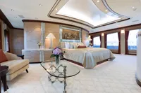 Luxurious yacht bedroom with elegant decor, featuring a large bed, glass table, and soft lighting.