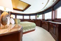 Luxurious yacht bedroom with elegant wood paneling, large windows, and plush bedding. Oceanco Custom 2001.