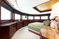Luxurious yacht bedroom with elegant wood paneling, large windows, and a plush bed. Oceanco Custom 2001.