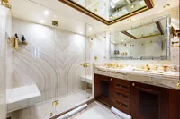 Luxurious yacht bathroom with marble shower, gold fixtures, and elegant wooden cabinetry. Oceanco Custom, 2001.