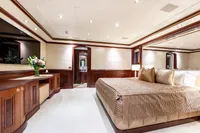Luxurious yacht bedroom with elegant wood paneling, plush bedding, and ambient lighting, Oceanco Custom 2001.